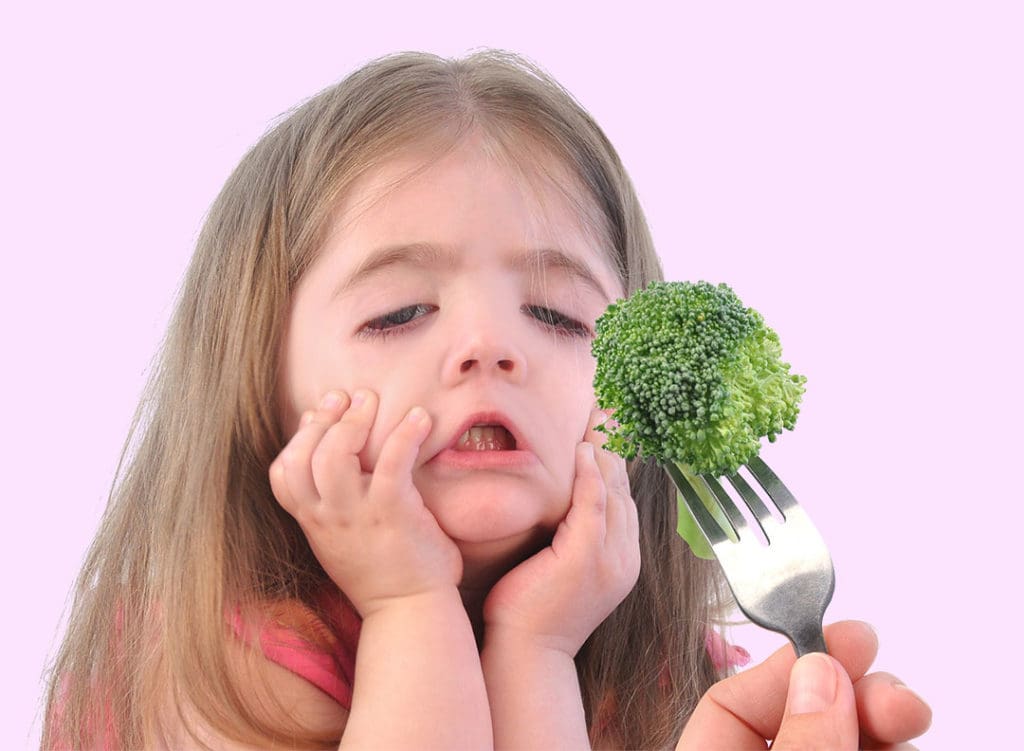 toddler girl looking distressingly at a piece of broccoli on a fork