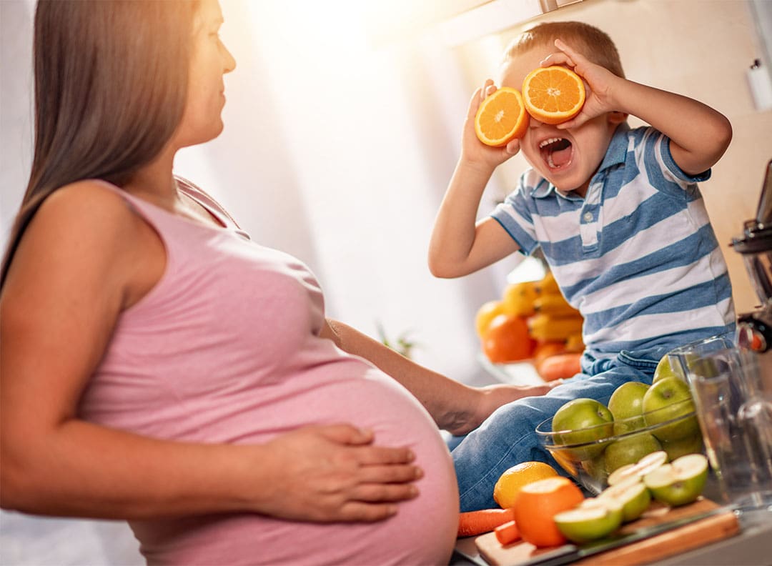 pregnant mother and young boy preparing fruit for a smoothie