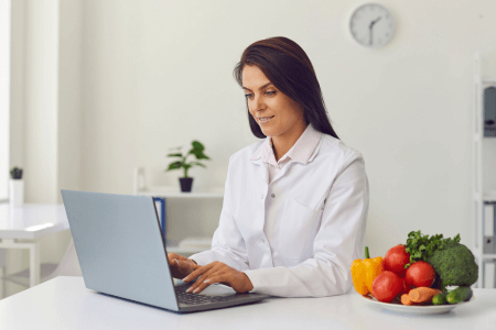 health practitioner in white lab coat working on laptop